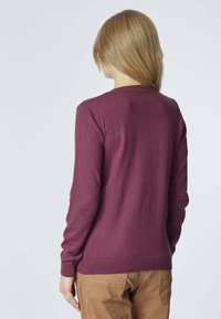 Maglione a maglia bordeaux con scollo rotondo, polsini e fondo a costine. La vista posteriore mostra una texture liscia e un design aderente.