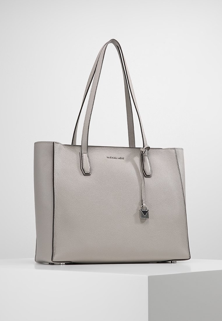 Borsa tote in pelle grigia con doppio manico, design strutturato, leggera brillantezza e un charm appeso a forma geometrica. Texture liscia e accenti lucidi.