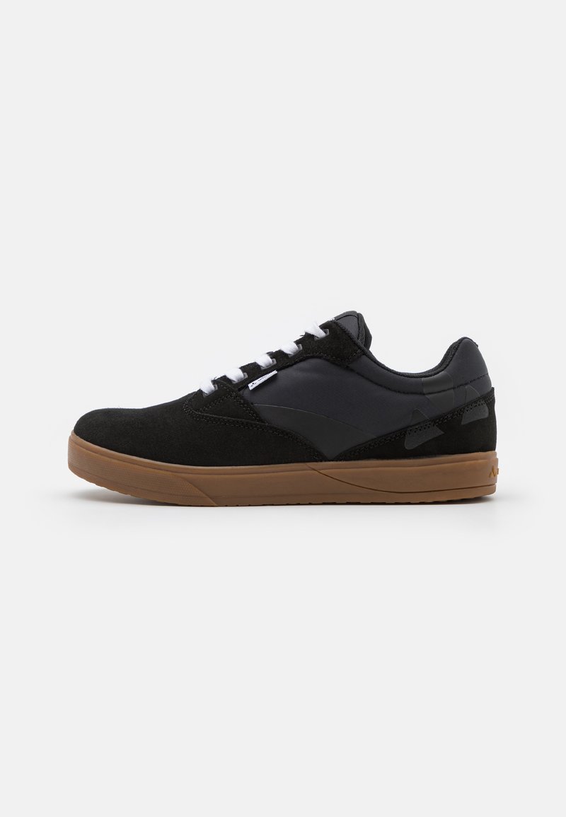 Czarny sneaker z kombinacją zamszu i materiałów syntetycznych, z brązową gumową podeszwą, białymi sznurowadłami i smukłym designem.