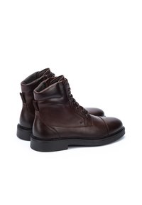 Botas de tobillo de cuero marrón con puntera redonda, con cordones en la parte delantera y una suela de goma negra resistente; cuentan con costuras reforzadas y lengüetas.