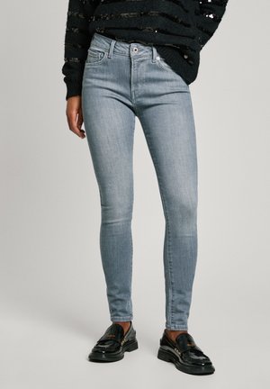 Light blue skinny jeans made of denim, featuring a mid-rise waist, subtle stitching, and a smooth texture, paired with black loafers.