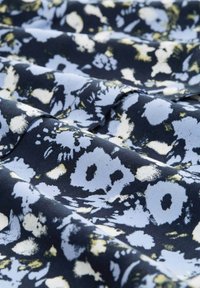 Kwiatowy materiał w granatowym odcieniu z jasnoniebieskimi i żółtymi akcentami, charakteryzujący się miękką teksturą, matowym wykończeniem i subtelnym połyskiem.