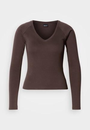 Καφέ μακρυμάνικο τοπ με V λαιμόκοψη και εφαρμοστή σιλουέτα, κατασκευασμένο από απαλό ελαστικό ύφασμα, με ραγκλάν μανίκια και καθαρές ραφές.