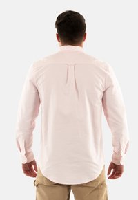 Chemise à manches longues, rayée rose, avec un pli au dos, des poignets à boutons et un ourlet arrondi, fabriquée en tissu léger.