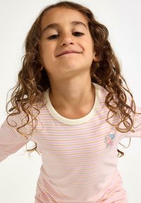 Proužkované tričko s dlouhým rukávem v pastelové růžové a bílé barvě, s krémově zbarveným výstřihem a drobnou květinovou výšivkou na hrudi.