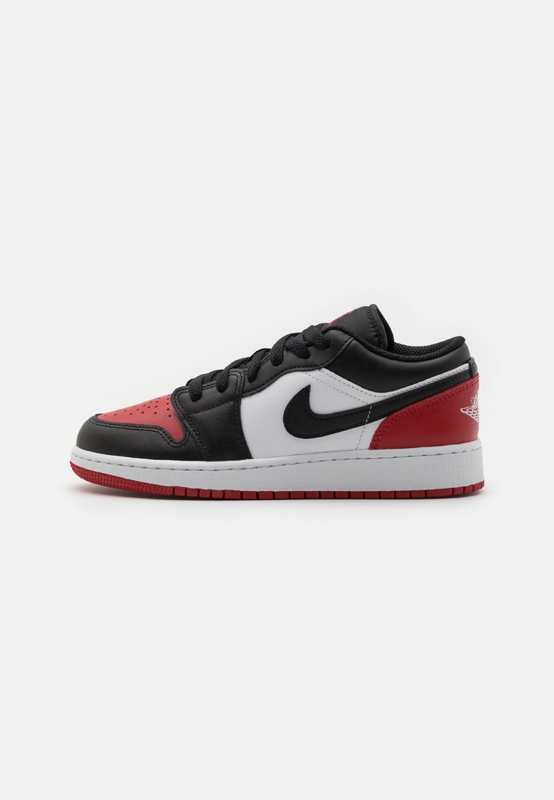 Sneaker in pelle nera con accenti rossi e bianchi, design basso, punta perforata e suola in gomma con motivo rosso.