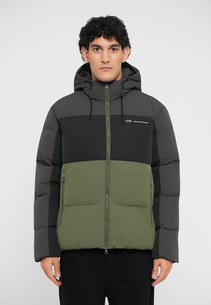 Giacca imbottita con un design a blocchi di colore in grigio scuro, nero e verde oliva. Include un cappuccio, una zip frontale e dettaglio del logo.