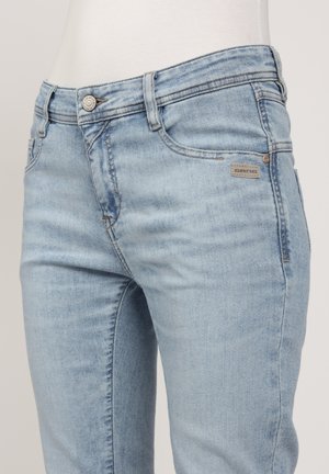 Hellblaue Denim-Jeans mit figurbetontem Schnitt, Fünf-Taschen-Design und Metallknopfverschluss. Mit Markenlabel auf der Vordertasche.