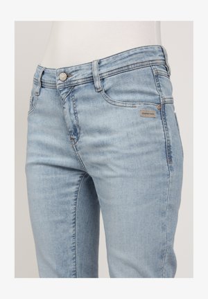 Light blue denim jeans with a fitted design, five-pocket styling, and metal button closure. Features brand label on the front pocket.