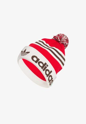 Red and white striped knitted beanie hat with a knitted pom-pom on top, featuring bold brown "adidas" branding and logo.