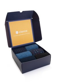 Sei calzini arrotolati in vari modelli e colori: blu navy, azzurro, blu scuro con righe e dettagli rossi, presentati in una scatola blu navy.
