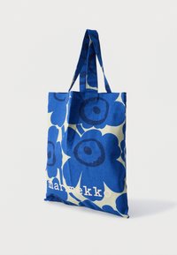 Τσάντα ώμου με μπλε λουλούδια, με μεγάλα σκούρα μπλε λουλούδια σε ανοιχτό φόντο. Κατασκευασμένη από ύφασμα, διαθέτει δύο μακριές λαβές και τυπωμένο λογότυπο.