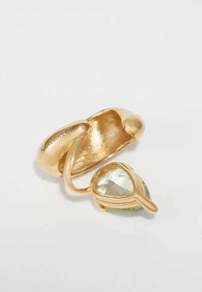 Gold-tone ring featuring a twisted design, set with a pear-shaped, light green gemstone. Smooth finish with a textured interior.