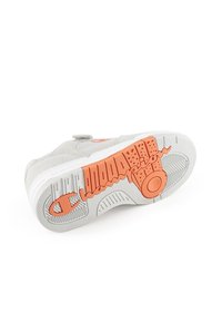Grauer Sneaker mit einer Gummisohle, die orangefarbene Akzente und strukturierte Muster aufweist. Das Design beinhaltet einen Riemen mit einem kreisförmigen Detail.