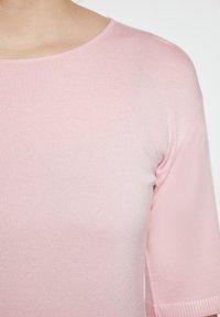 Vaaleanpunainen ribbikuvioitu neulepaita, jossa on pyöreä pääntie ja lyhyet hihat. Sujuva pinta hienovaraisella kiillolla ja tiukka malli.
