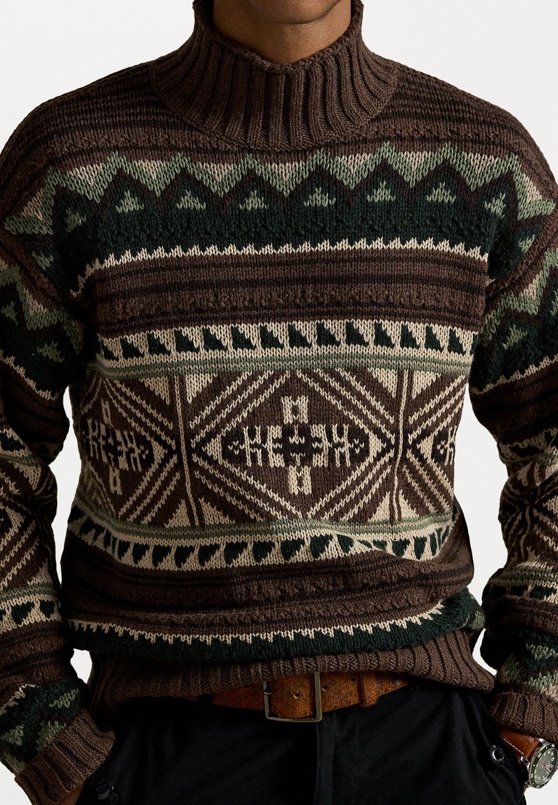 Brun stickad tröja med hög krage, med geometriska mönster i beige och grönt. Texturerad tyg och ribbade muddar och nederkant.