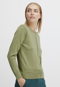 Cardigan vert en tissu tricoté doux, avec un col rond, une fermeture par boutons, des poignets et un ourlet côtelés. Texture lisse avec de subtiles variations.