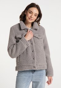 Szara, teksturowana bluza polarowa z kołnierzem, zatrzaskami i kieszeniami z przodu. Stylizowana w luźnym kroju i z długimi rękawami.