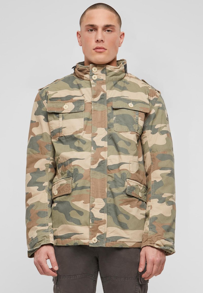 Geacă camuflaj în nuanțe de bej și verde, cu guler înalt, închidere cu nasturi și mai multe buzunare frontale cu clapetă. Finisaj texturat.