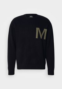 Suéter negro de punto con puños y dobladillo acanalados. Presenta una "M" verde de gran tamaño en el lado izquierdo. Cuello redondo, textura suave.