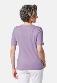 Paarse T-shirt met korte mouwen van zachte stof, met een ronde hals en een aansluitend ontwerp, gecombineerd met witte broek.