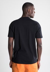 Black cotton t-shirt with short sleeves, crew neck, and a plain design, highlighted against a neutral background.