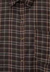 Camisa de cuadros marrón con un diseño abotonado, que presenta líneas grises, beige y negras. Bolsillo en el pecho izquierdo con cierre de botón, textura suave.