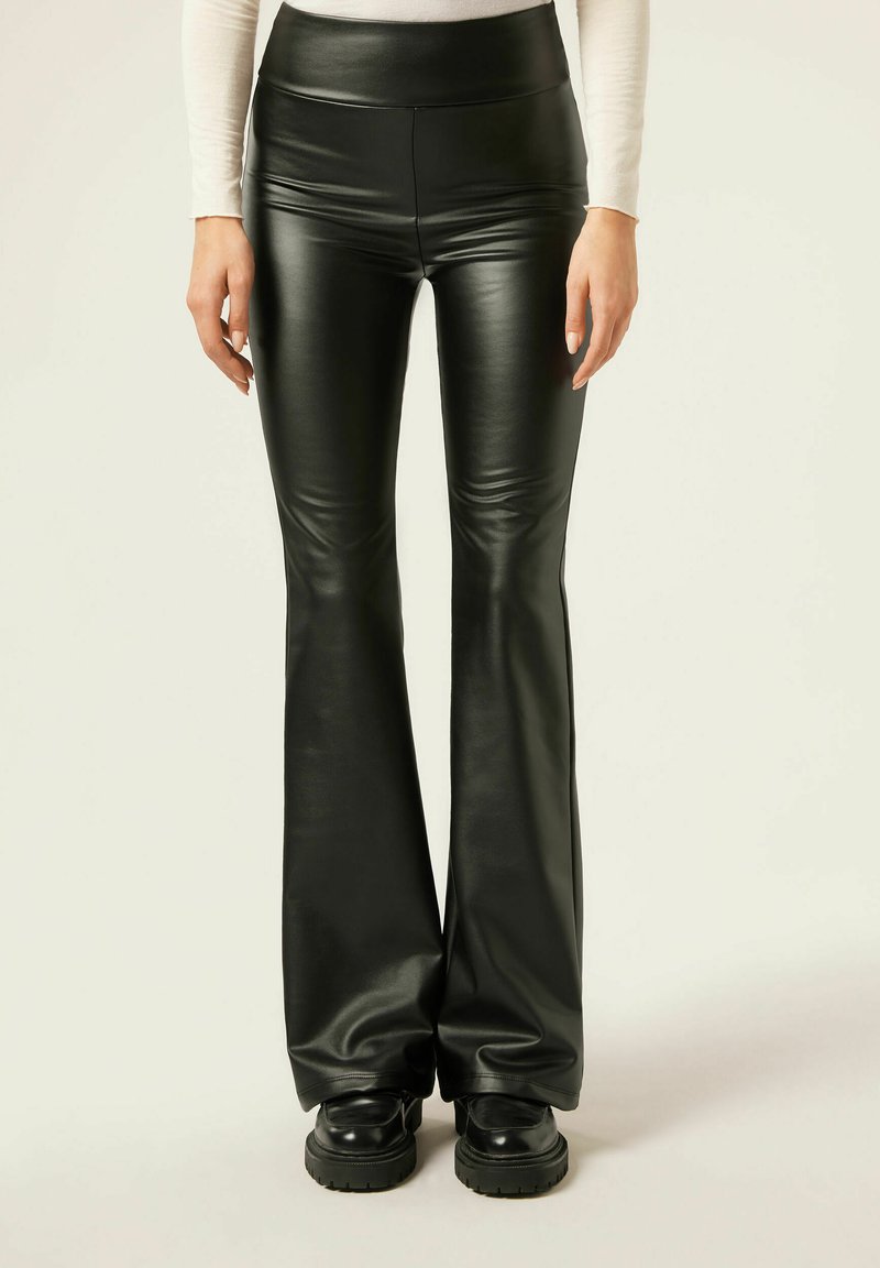Zwarte neplederen flare pants met een hoge tailleband, voorzien van een glanzende afwerking en een gladde textuur, gecombineerd met chunky zwarte laarzen.