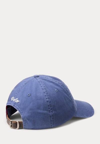 Sinine Polo kaubamärgi pesapalli nokamüts reguleeritava pruuni nahast rihma ja metallist pandlaga, vaadates tagantpoolt ja kergelt külje pealt.