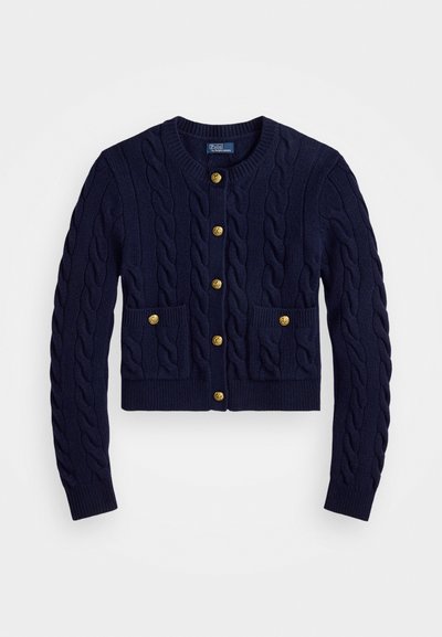 Tummansininen neulecardigan, jossa on kaapelikuvio, kultaiset napit ja kaksi etutaskua. Lyhyempi malli, ribattu hihansuut ja helma.