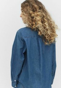 Jasnoniebieska koszula dżinsowa z długimi rękawami, mankietami na guziki i detalami na plecach. Gładka tekstura z klasycznym krojem.