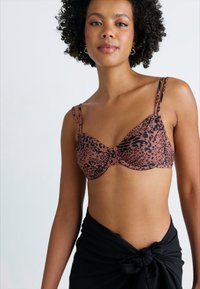 Brun leopardmønster bh med underwire, med tynne, justerbare stropper og en rynket midt. Modell iført en svart knyttet omslagskjørt.