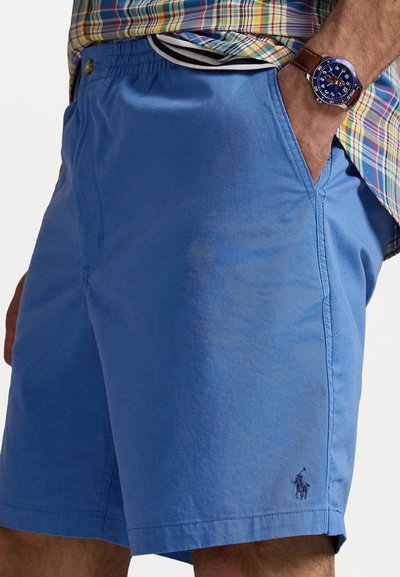 Shorts bleus en tissu léger avec une taille élastique, des poches latérales et un logo brodé discret sur l'ourlet.