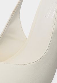 Κοντινό πλάνο λευκού δερμάτινου παπουτσιού με χαμηλό τακούνι, στρογγυλεμένη μύτη και λεία ραφή κατά μήκος των άκρων.