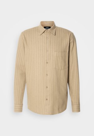 Beige skjorte med knapper og vertikale blå striper, lange ermer, en enkelt brystlomme, og klassisk krage. Myk tekstur.