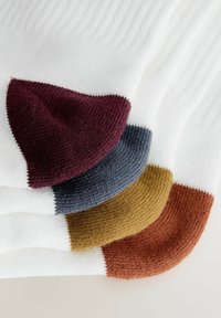 Calze bianche con texture a coste, con dettagli colorati sul tallone e sulla punta in bordeaux, blu navy, senape e terracotta.
