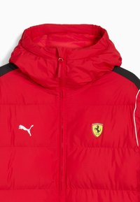 Rød pufferjakke med hætte, med sorte skulderdetaljer, hvid piping, Puma-logo og et gult Ferrari-emblem på brystet.