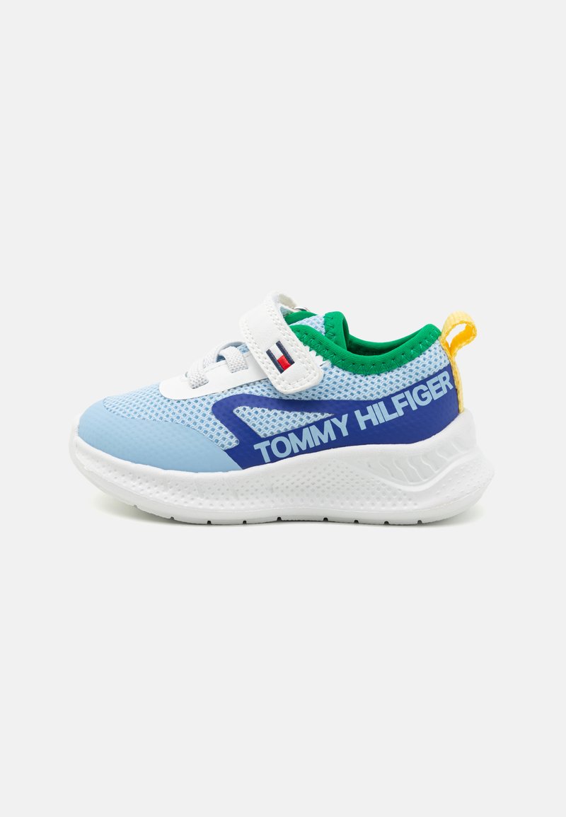 Blaues atmungsaktives Sportschuh mit weißen und grünen Akzenten, ausgestattet mit einem Klettverschluss, dicker weißer Sohle und "TOMMY HILFIGER" Branding in Blau.