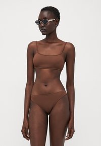 Brown ribbed bikini set featuring a rectangular bralette top with thin straps and matching low-rise bottom. Matte texture with minimal detailing.