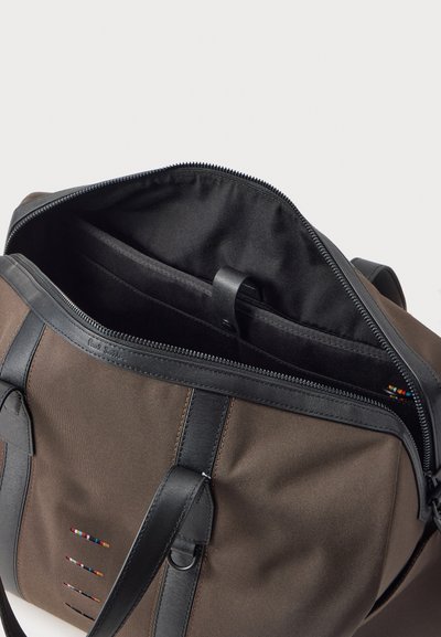 Καφέ υφασμάτινη τσάντα ώμου με μαύρες δερμάτινες λαβές, ανοιχτό φερμουάρ που αποκαλύπτει μαύρο εσωτερικό με επενδυμένη θήκη και πολύχρωμη λεπτομέρεια ραφής.