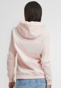 Helle rosa Kapuzenjacke aus weichem Stoff, mit einer Kängurutasche und verstellbarem Kordelzug in der Kapuze, sowie gerippten Bündchen und Saum.