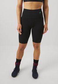 Shorts bike neri a vita alta realizzati in tessuto elasticizzato con una texture liscia, con un piccolo logo verde sulla cintura.