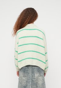 Ανοιχτό πράσινο ριγωτό πουλόβερ από μαλακό πλεκτό υλικό. Διαθέτει φαρδύ γιακά και ριμπ μανσέτες, εμφανισμένο από πίσω.