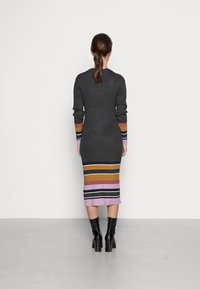 Robe tricotée avec une texture côtelée. Haut gris foncé se dégradant en rayures horizontales jaune, orange, rose, noir et blanc. Longueur mi-mollet.