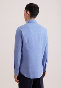 Jasnoniebieska wzorzysta koszula o dopasowanym kroju, z guzikami na mankietach i gładką fakturą; posiada subtelny geometryczny nadruk.