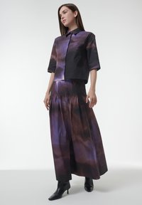 Purple and black short-sleeve shirt and matching long skirt with a fluid, abstract pattern. Material appears smooth with a soft sheen.