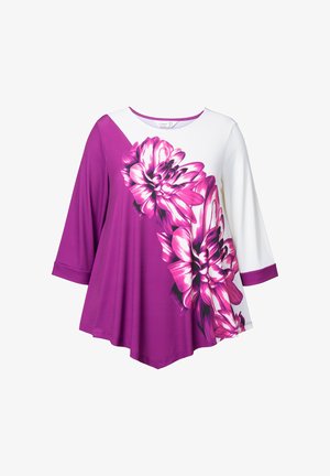 Lila und weiße Tunika mit einem großen pinken Blumenmuster. Weite Ärmel und ein abgerundeter Halsausschnitt, aus einem weichen, glatten Stoff gefertigt.