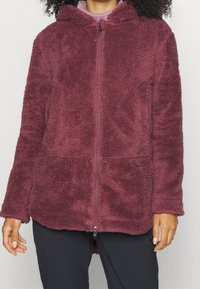 Polarowy hoodie w głębokim burgundzie z pełnym zapięciem na zamek, przednimi kieszeniami i miękką teksturą; posiada kaptur i luźny krój.