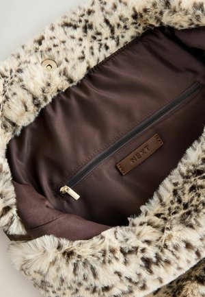 Faux fur -laukun sisäosa, jossa on pilkullinen vaaleanbeige ja ruskea kuvio, tumma ruskea kangaspäällyste ja vetoketjullinen tasku.
