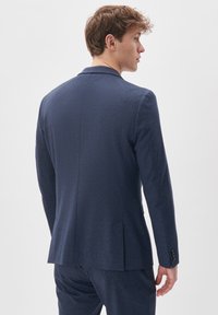 Navy blue blazer in a textured fabric, featuring a two-button closure and notch lapels, with a single vent and buttoned cuffs.